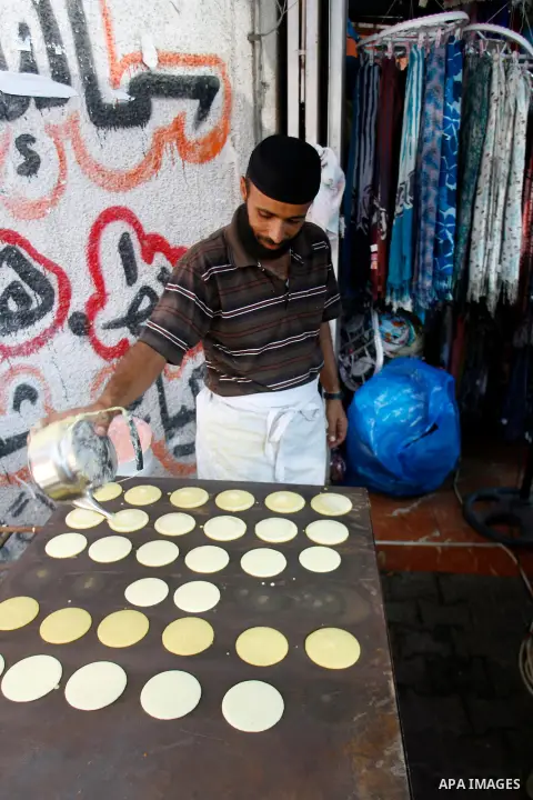 A Palestinian man prepares traditional pancake known as "Qatayef" consumed during Ramadan in Rafah in the south of Gaza strip, on July 22, 2012. Muslims around the world abstain from eating, drinking and conducting sexua...
