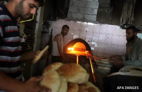 A Palestinian man bakes loaves of bread in his traditional mud oven during Ramadan in Jabalya refugee camp, northen Gaza Strip on July 23, 2012. Muslims around the world abstain from eating, drinking and conducting sexua...