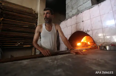 A Palestinian man bakes loaves of bread in his traditional mud oven during Ramadan in Jabalya refugee camp, northen Gaza Strip on July 23, 2012. Muslims around the world abstain from eating, drinking and conducting sexua...