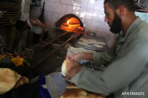 A Palestinian man helps baker to bake bread in his traditional mud oven during Ramadan in Jabalya refugee camp, northen Gaza Strip on July 23, 2012. Muslims around the world abstain from eating, drinking and conducting s...