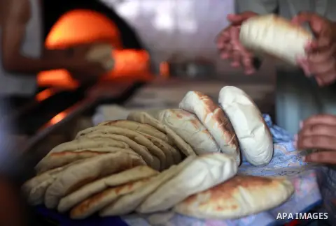 A Palestinian man bakes loaves of bread in his traditional mud oven during Ramadan in Jabalya refugee camp, northen Gaza Strip on July 23, 2012. Muslims around the world abstain from eating, drinking and conducting sexua...