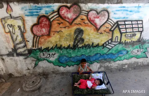 A palestinian child helping his sister to sleep in front of their home in the Beach refugee camp in Gaza City before Breaking fast on the third day of the Holy month of Ramadan, in Gaza Strip, 24 July 2012. Muslims throu...