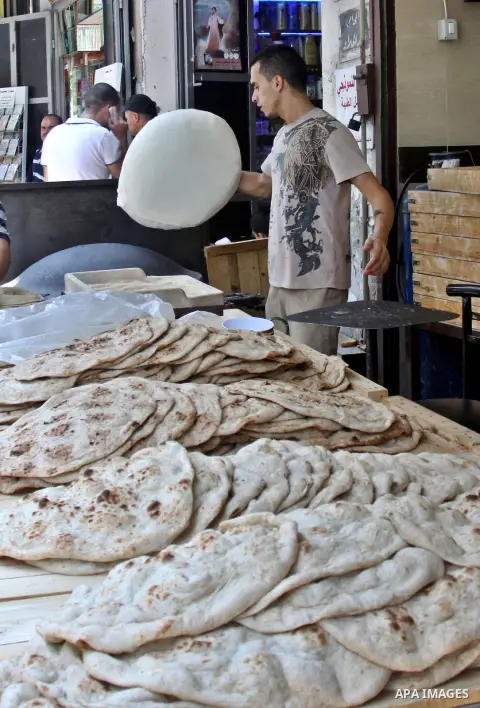 A Palestinian man bakes loaves of bread in his traditional mud oven during Ramadan in the West Bank city of Nablus on July 25, 2012. Muslims around the world abstain from eating, drinking and conducting sexual relations...