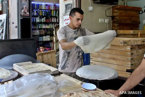 A Palestinian man bakes loaves of bread in his traditional mud oven during Ramadan in the West Bank city of Nablus on July 25, 2012. Muslims around the world abstain from eating, drinking and conducting sexual relations...