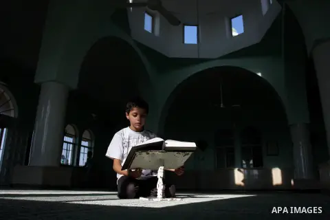 A Palestinian child reads the holy Qur'an at the mosque in West Bank City of Ramallah, on 25 July 2012. Muslims around the world refrain from eating, drinking and sexual intercourse from dawn till dusk during Ramadan, th...