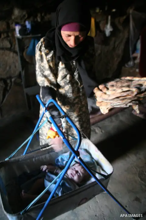 A Palestinian woman looks after her children in a cave, where they live, near the Palestinian village of Jimba, south of Yatta, near the West Bank town of Hebron on July 25, 2012. The Israeli Defence Minister, Ehud Barak...