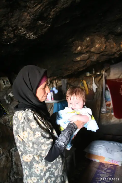 A Palestinian woman looks after her children in a cave, where they live, near the Palestinian village of Jimba, south of Yatta, near the West Bank town of Hebron on July 25, 2012. The Israeli Defence Minister, Ehud Barak...