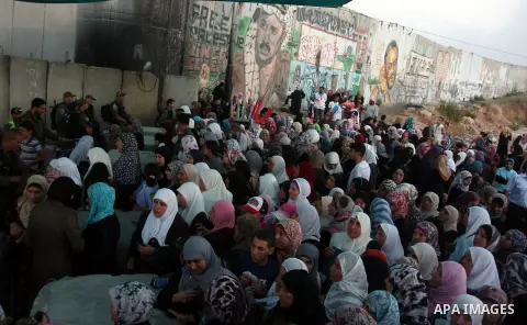 Palestinian women wait to show their identity cards to Israeli security officers at Qalandiya checkpoint outside the West Bank city of Ramallah July 27, 2012, as they make their way to Jerusalem on the second Friday of t...