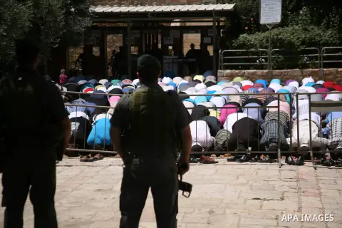 Israeli border policemen stand guard as Palestinian men perform the second Friday prayers of the Muslim fasting month of Ramadan outside the Ibrahimi Mosque or the Tomb of the Patriarchs in the West Bank city of Hebron o...