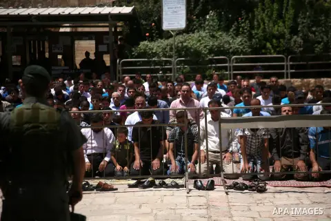Israeli border policemen stand guard as Palestinian men perform the second Friday prayers of the Muslim fasting month of Ramadan outside the Ibrahimi Mosque or the Tomb of the Patriarchs in the West Bank city of Hebron o...