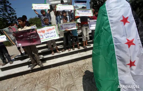 Palestinian children hold a Syrian revolution flag during a protest against Syria's President Bashar al-Assad and support of Syrian Children at the Al joundi Al Majhoul in Gaza City on July 28, 2012. Photo by Ashraf Amra