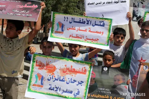 Palestinian children hold a Syrian revolution flag during a protest against Syria's President Bashar al-Assad and support of Syrian Children at the Al joundi Al Majhoul in Gaza City on July 28, 2012. Photo by Ashraf Amra