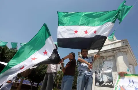 Palestinian children hold a Syrian revolution flag during a protest against Syria's President Bashar al-Assad and support of Syrian Children at the Al joundi Al Majhoul in Gaza City on July 28, 2012. Photo by Ashraf Amra