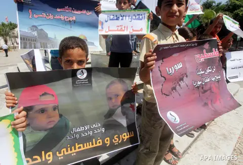 Palestinian children hold a Syrian revolution flag during a protest against Syria's President Bashar al-Assad and support of Syrian Children at the Al joundi Al Majhoul in Gaza City on July 28, 2012. Photo by Ashraf Amra