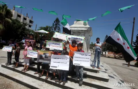 Palestinian children hold a Syrian revolution flag during a protest against Syria's President Bashar al-Assad and support of Syrian Children at the Al joundi Al Majhoul in Gaza City on July 28, 2012. Photo by Ashraf Amra