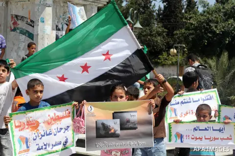 Palestinian children hold a Syrian revolution flag during a protest against Syria's President Bashar al-Assad and support of Syrian Children at the Al joundi Al Majhoul in Gaza City on July 28, 2012. Photo by Ashraf Amra