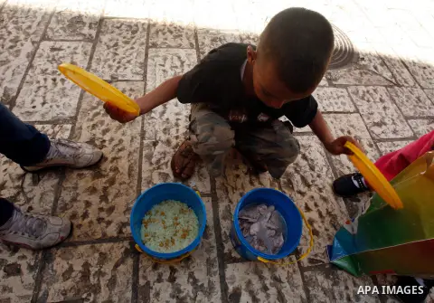 A Palestinian child looks at food cans recieved from volunteers during the fasting month of Ramadan in Jerusalem on July 28, 2012. During Ramadan eating, drinking, sex and smoking is banned and restaurants are forbidden...