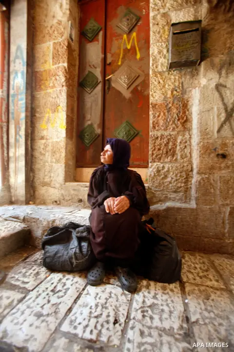 A Palestinian indigent woman waits to recieve food from volunteers during the fasting month of Ramadan in Jerusalem on July 28, 2012. During Ramadan eating, drinking, sex and smoking is banned and restaurants are forbidd...