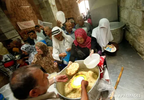 Palestinian indigent Muslims recieve food from volunteers during the fasting month of Ramadan in Jerusalem on July 28, 2012. During Ramadan eating, drinking, sex and smoking is banned and restaurants are forbidden to ser...