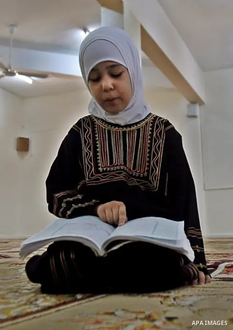 A Palestinian girl reads the holy Qur'an at mosque in the West bank city of Nablus, on 29 July 2012. Muslims around the world refrain from eating, drinking and sexual intercourse from dawn till dusk during Ramadan, the h...
