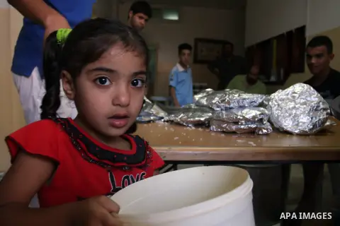 A Palestinian indigent girl recieves food from volunteers during the fasting month of Ramadan in In the West Bank, Al-Amari refugee camp near Ramallah July 29, 2012. During Ramadan eating, drinking, sex and smoking is ba...