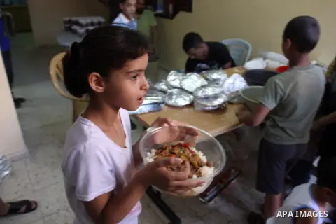 Palestinian indigent Muslims recieve food from volunteers during the fasting month of Ramadan in In the West Bank, Al-Amari refugee camp near Ramallah July 29, 2012. During Ramadan eating, drinking, sex and smoking is ba...
