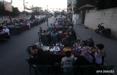 Families of Palestinian prisoners in Israeli jails attend the collective breaking fast organized by the Association of "Wa'ed" and funded by the Turkish relief "IHH" in front of the Red Cross headquarters during the holy...
