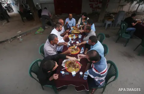 Families of Palestinian prisoners in Israeli jails attend the collective breaking fast organized by the Association of "Wa'ed" and funded by the Turkish relief "IHH" in front of the Red Cross headquarters during the holy...