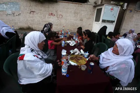 Families of Palestinian prisoners in Israeli jails attend the collective breaking fast organized by the Association of "Wa'ed" and funded by the Turkish relief "IHH" in front of the Red Cross headquarters during the holy...
