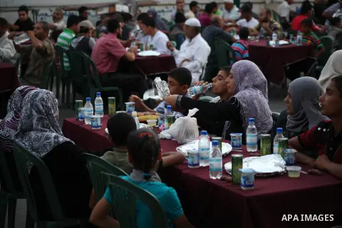 Families of Palestinian prisoners in Israeli jails attend the collective breaking fast organized by the Association of "Wa'ed" and funded by the Turkish relief "IHH" in front of the Red Cross headquarters during the holy...