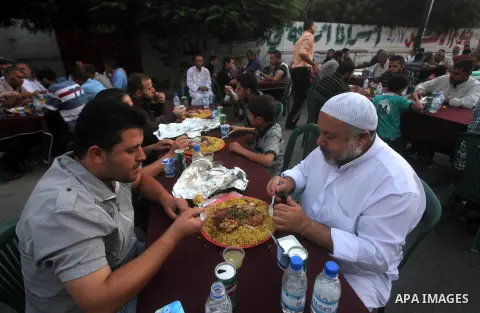 Families of Palestinian prisoners in Israeli jails attend the collective breaking fast organized by the Association of "Wa'ed" and funded by the Turkish relief "IHH" in front of the Red Cross headquarters during the holy...