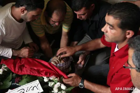 Palestinian mourners over the body of Akram Badr, 46, during a funeral in the village of Beitillu near in the West Bank city of Ramallah, Tuesday, July 31, 2012. Badr was killed at a checkpoint by the Israeli security fo...