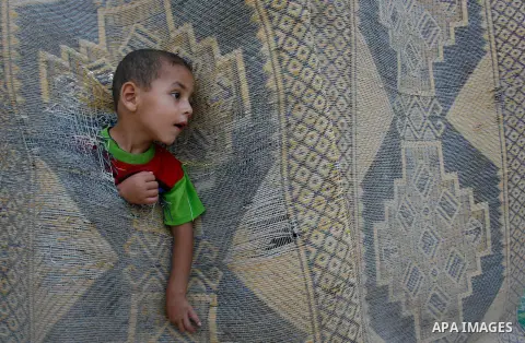 A Palestinian indigent refugee child plays in between makeshift tents during holy month of Ramadan, in Rafah refugee camp southern Gaza strip, 31 July 2012 . Photo by Eyad Al Baba