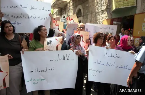 Palestinian women hold signs during a demonstration protesting violence against women held at the spot where a woman's throat was allegedly slashed by her husband on Monday, in the West Bank town of Bethlehem, Wednesday,...
