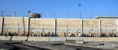 Palestinian men wait in line to cross to Jerusalem at the military checkpoint of Qalandia, near the West Bank city of Ramallah on Aug. 3, 2012, Palestinian Muslims are heading to Jerusalem to attend the third Friday pray...