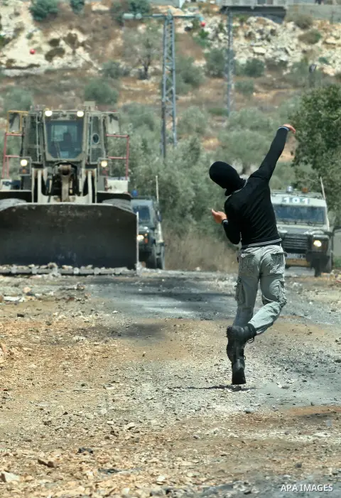 A Palestinian protestor throws stones at Israeli truck during a demonstration against the expropriation of Palestinian land by Israel in the village of Kafr Qaddum, near the West Bank city of Nablus on Aug. 03, 2012. Pho...