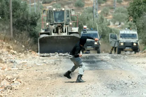 A Palestinian protestor throws stones at Israeli truck during a demonstration against the expropriation of Palestinian land by Israel in the village of Kafr Qaddum, near the West Bank city of Nablus on Aug. 03, 2012. Pho...