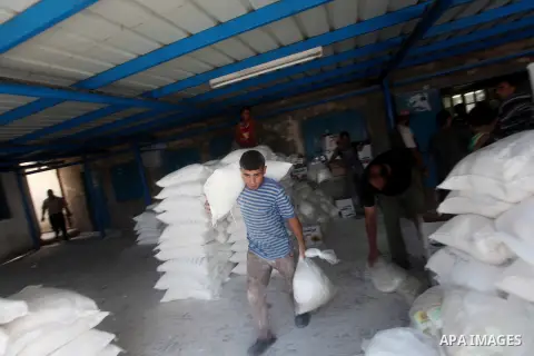 A Palestinian youth carries a sack of flour at a UN Relief and Works Agency (UNRWA) warehouse in the Shati refugee camp, in Gaza City, on Aug. 05, 2012. UNRWA launched Sunday its Gaza Ramadan Appeal for 5000 food parcels...