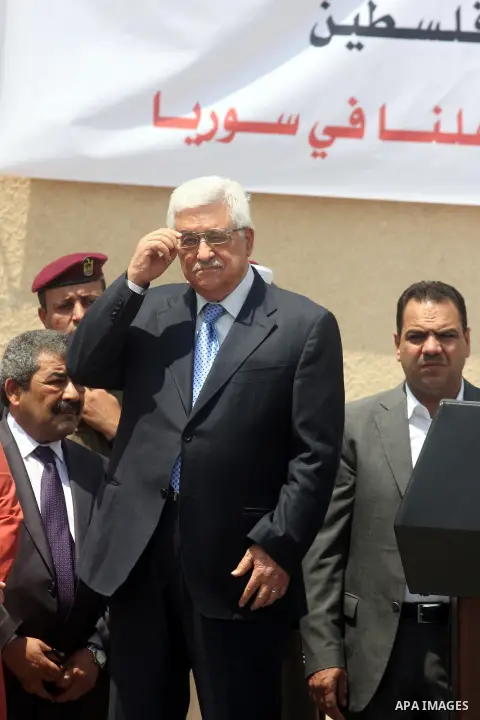 Palestinian President Mahmoud Abbas, accompanied by other officials as he waves to a convoy of trucks carrying food and medical supplies, which reportedly were provided by the Palestinian people, leaving Ramallah bound f...