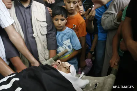 Mourners over the body of a Palestinian militant Eid Hejazi during his funeral in Rafah, southern Gaza Strip, Sunday, Aug. 5, 2012. Hejazi was killed on an Israeli air strike on Sunday and was a member of the Popular Res...