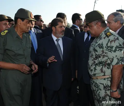 Egypt's President Mohamed Mursi gestures, while Field Marshal Hussein Tantawi, and an army general look on at a checkpoint in al-Arish August 6, 2012. Egypt branded Islamist gunmen who killed 16 police near the Israeli b...