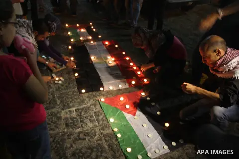 Palestinian youths light candles and place them on Palestinian and Egyptian flags on August 8, 2012, in the West Bank city of Ramallah, in memory of the 16 Egyptian soldiers who were killed in a militant ambush on August...