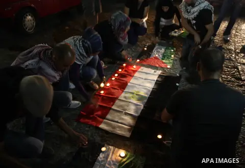 Palestinian youths light candles and place them on Palestinian and Egyptian flags on August 8, 2012, in the West Bank city of Ramallah, in memory of the 16 Egyptian soldiers who were killed in a militant ambush on August...