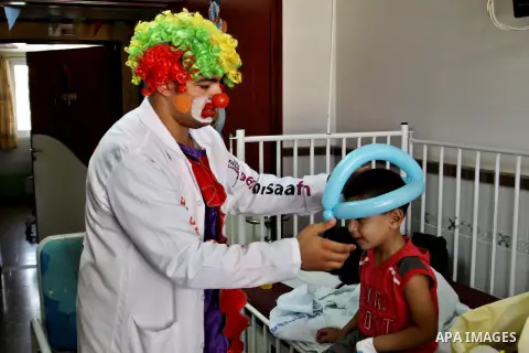 A Palestinian doctor dressed as clown, plays with a child during a physiological treatment session at a hospital in the West Bank city of Nablus, on Aug. 09, 2012. Photo by Nedal Eshtayah