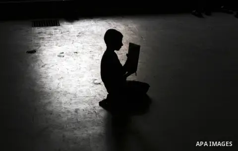 A Palestinian boy is silhouetted against the reflection of a window in the floor of the Al-Omari mosque as he reads in a copy of the Holy Koran during prayers in the Gaza Strip, 09 August 2012. Muslims throughout the wor...