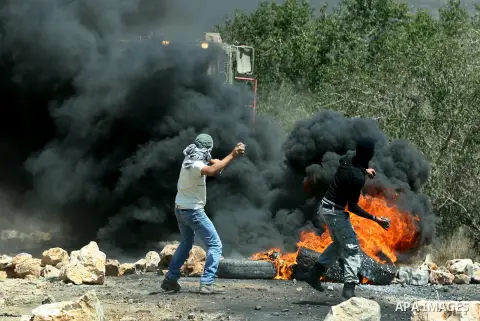 Palestinian protesters throw stones at Israeli bulldozer during a demonstration against the expropriation of Palestinian land by Israel in the village of Kafr Qaddum, near the West Bank city of Nablus, on August 10, 2012...