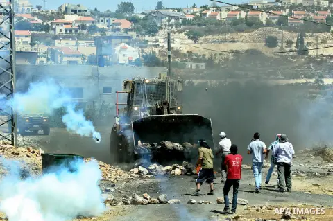 Palestinian protesters throw stones at Israeli bulldozer during a demonstration against the expropriation of Palestinian land by Israel in the village of Kafr Qaddum, near the West Bank city of Nablus, on August 10, 2012...