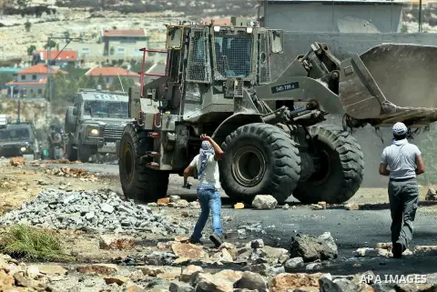 Palestinian protesters throw stones at Israeli bulldozer during a demonstration against the expropriation of Palestinian land by Israel in the village of Kafr Qaddum, near the West Bank city of Nablus, on August 10, 2012...