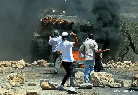 Palestinian protesters throw stones at Israeli bulldozer during a demonstration against the expropriation of Palestinian land by Israel in the village of Kafr Qaddum, near the West Bank city of Nablus, on August 10, 2012...