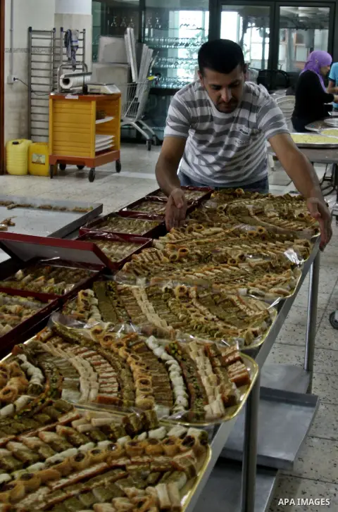 A Palestinian vendor displays his goods "traditional nut cookies" before the upcoming Eid al-Fitr holidays at a bakery in the West Bank city of Nablus, on Aug. 14, 2012. Muslims will celebrate Eid al-Fitr that marks the...